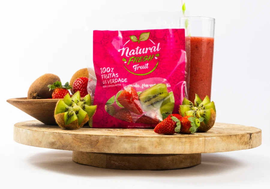 Embalagem Natural Fresh Fruit com kiwi, morango e suco batido sobre tábua de madeira
